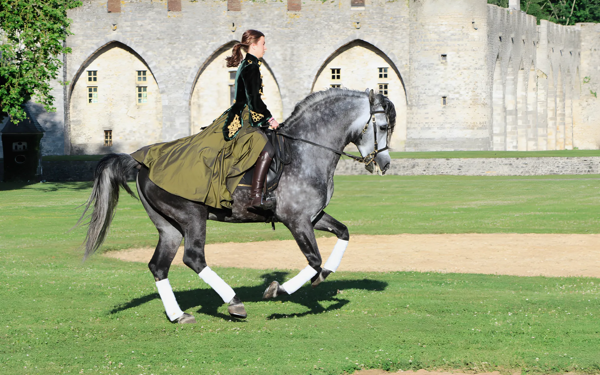 Une cavalière en dressage devant les arcades de la courtine