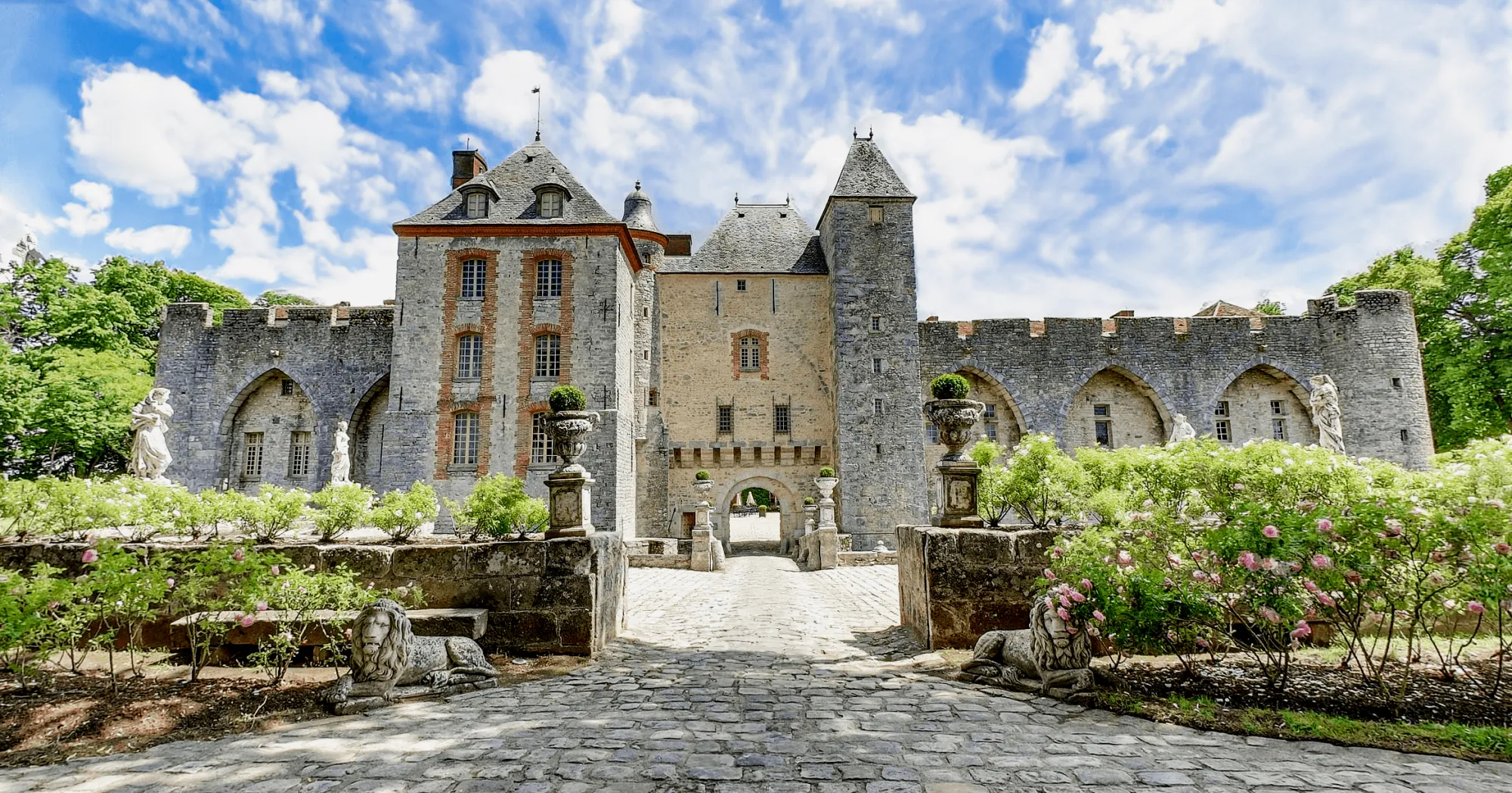La façade du château depuis la roseraie, les lions de pierre au premier plan