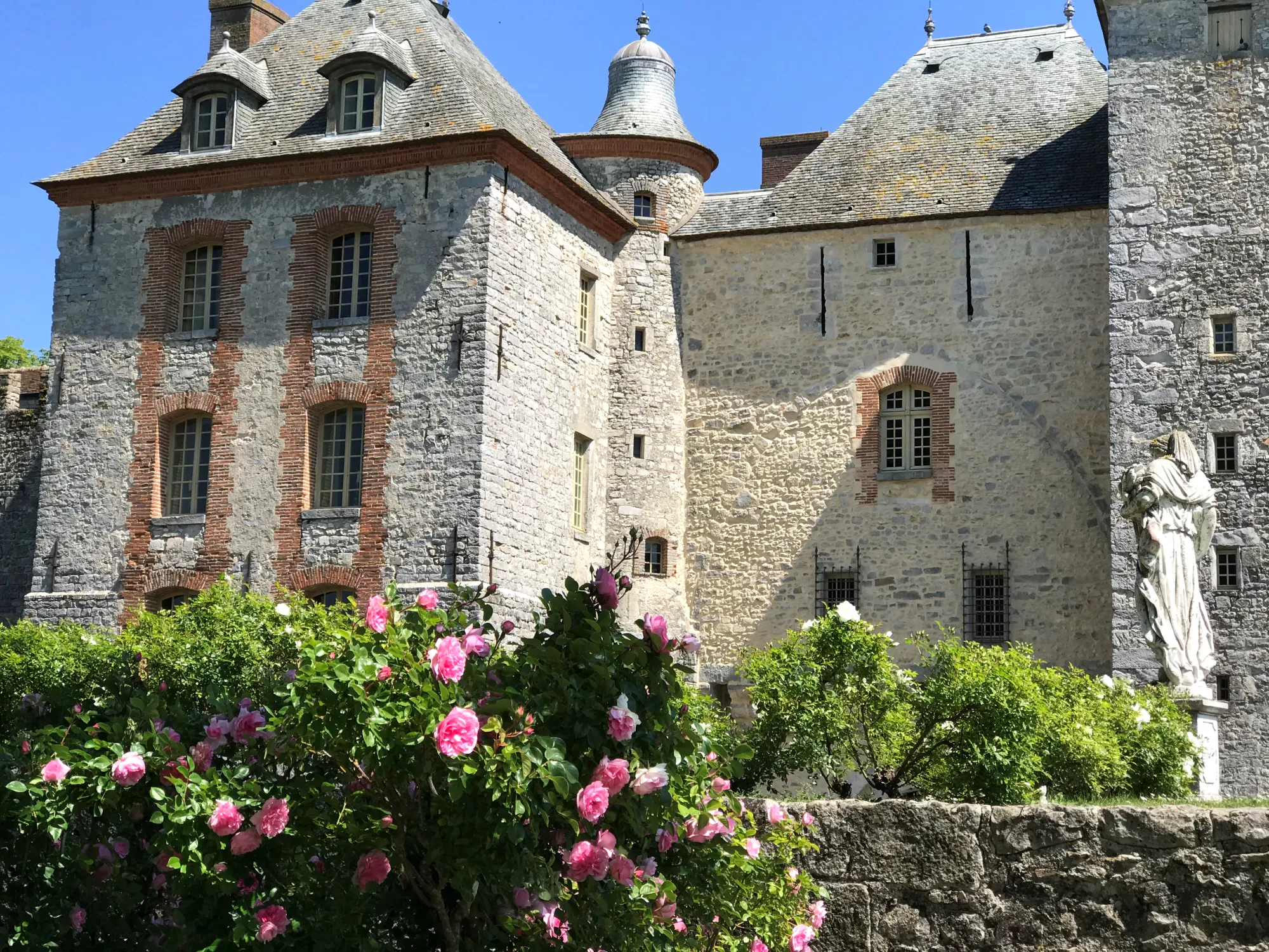 La façade nord et ses tourelles au-dessus d'un massif de roses