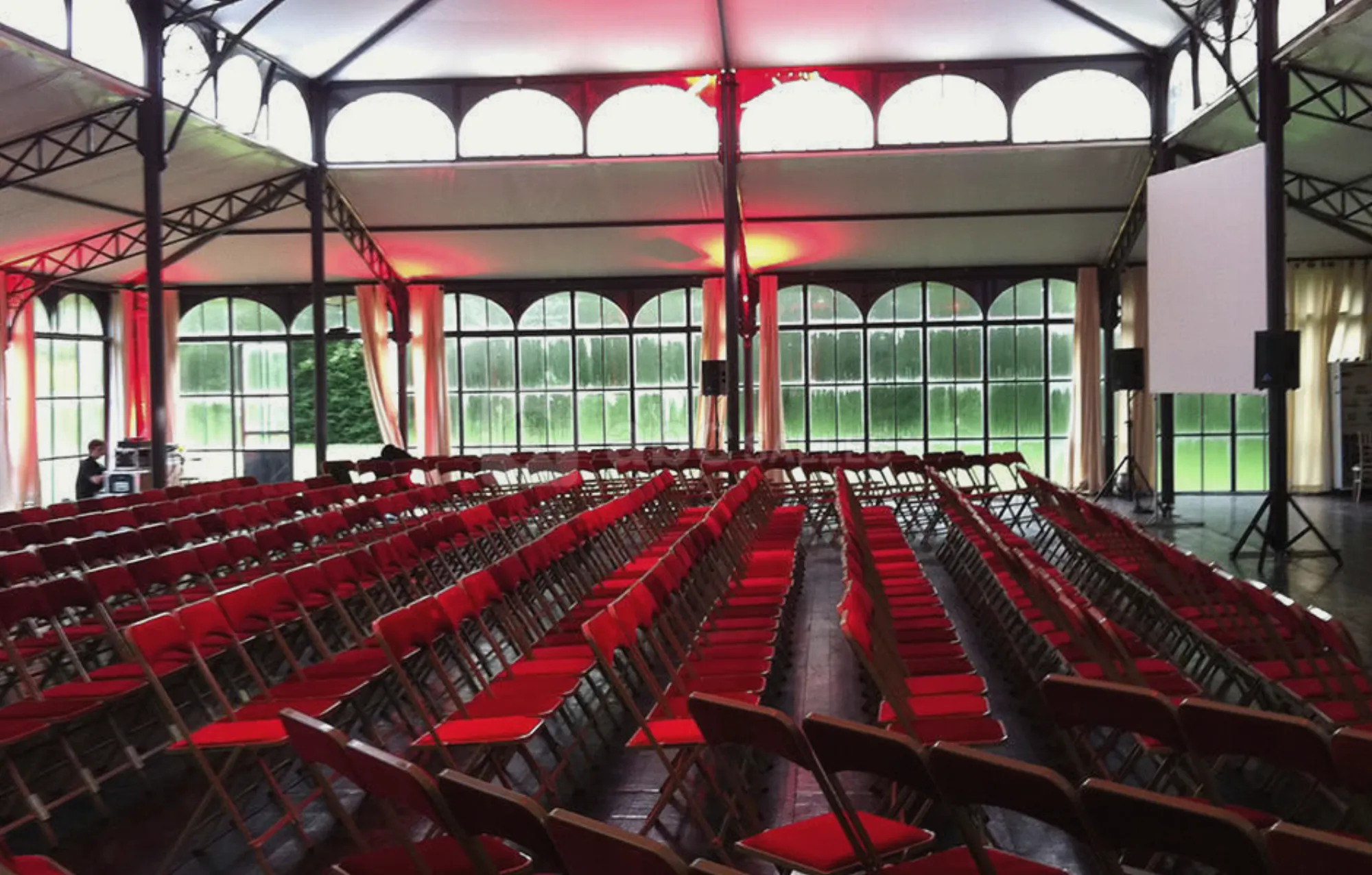 L'Orangerie en plénière, des rangées de chaises rouges sous la verrière
