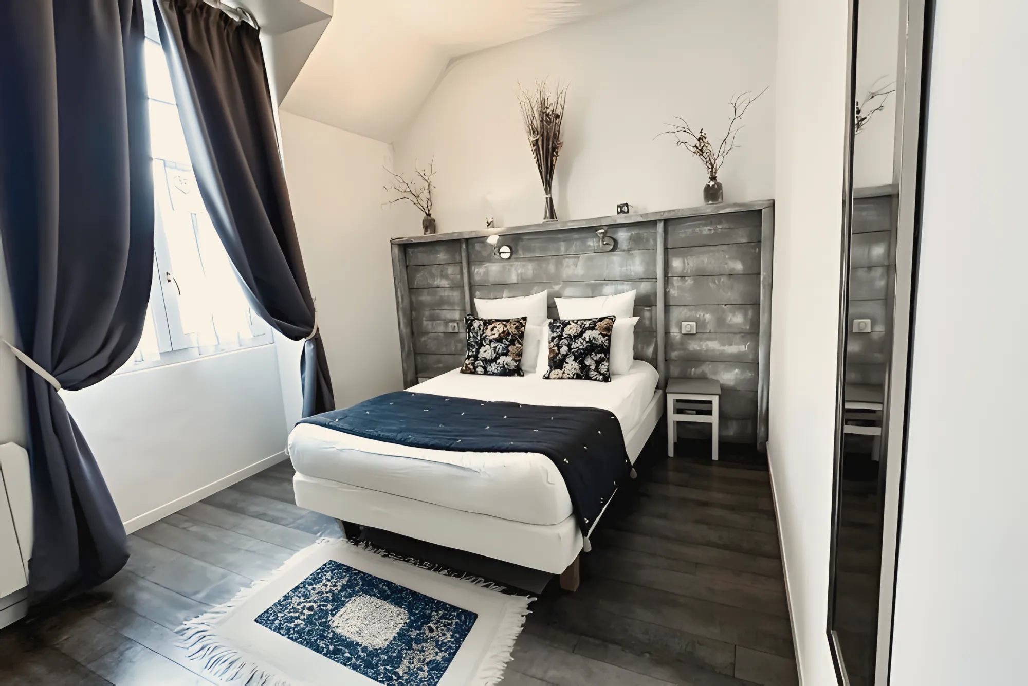 Une chambre du gîte, rideaux bleu nuit, tête de lit en bois gris