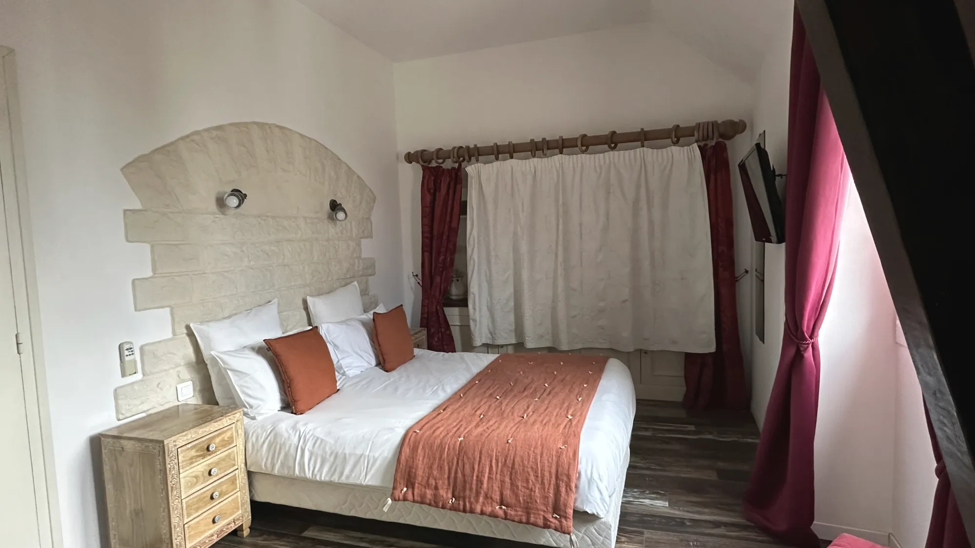 Une chambre du gîte, tête de lit en pierre, jeté rouille